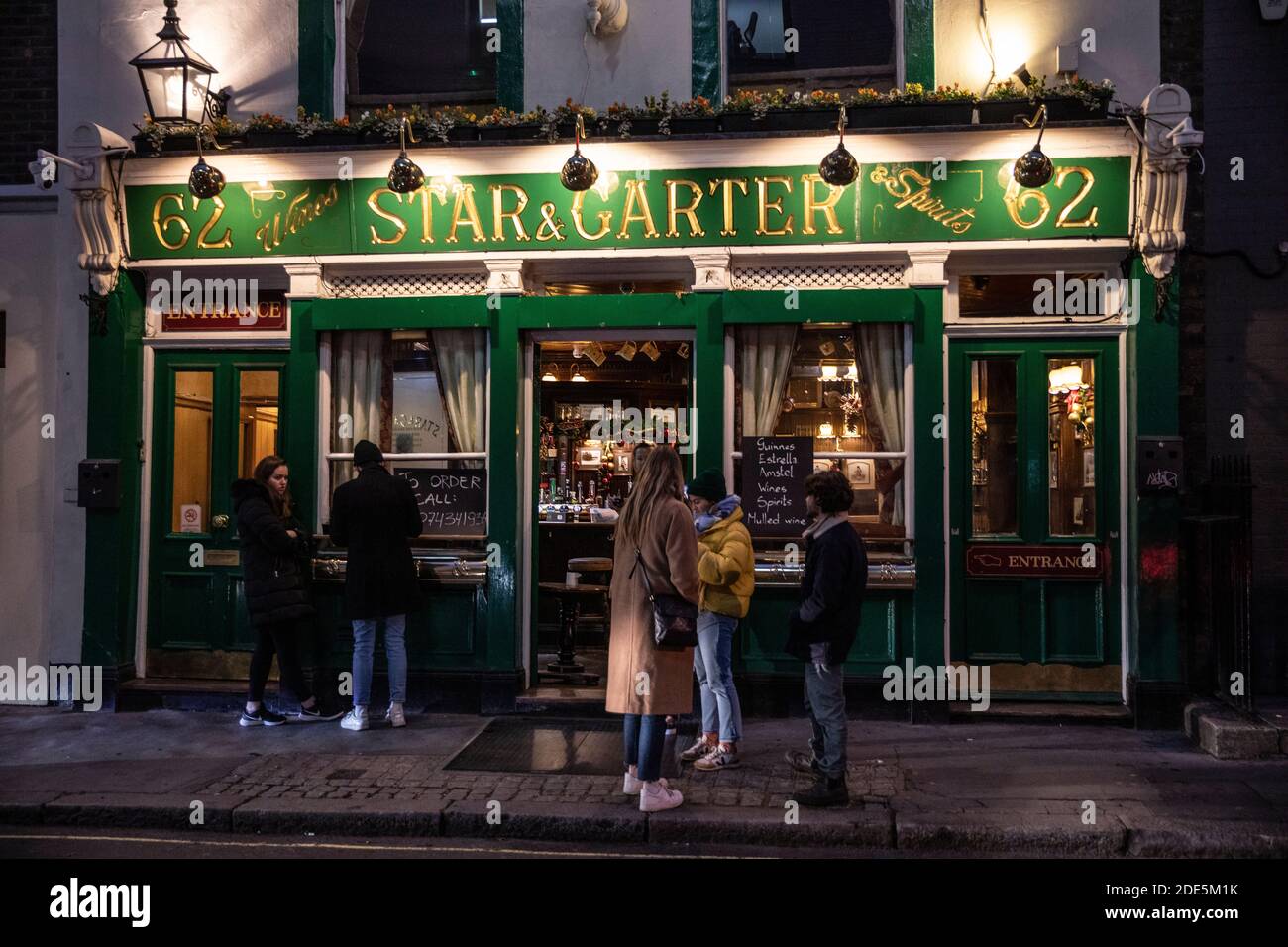 People stand outside The Star and Garter pub in Soho drinking takeaway drinks during the