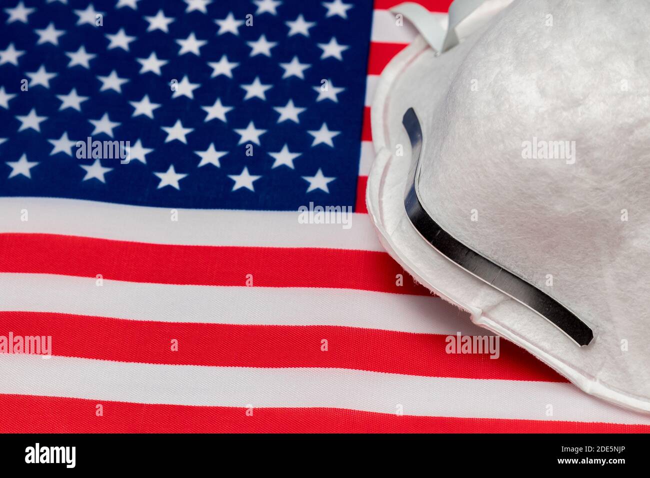 N95 face mask on United States of America flag. Concept of Covid-19 coronavirus pandemic, face mask, face covering mandate, and stay at home order Stock Photo