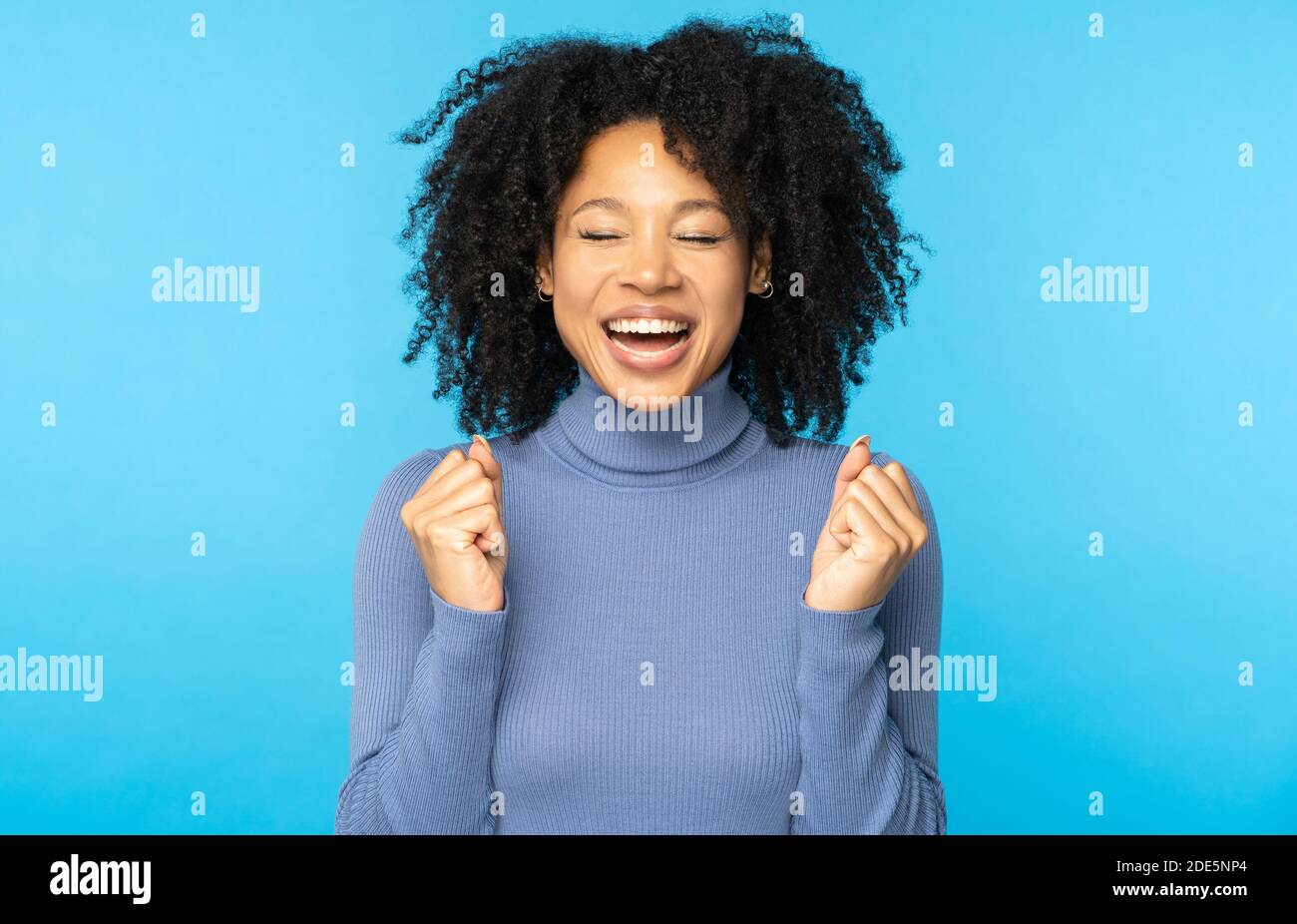 Yes, I did it! Excited Afro American woman screaming with joy celebrating victory win success, clenching her fists, rejoicing triumph feeling winner, Stock Photo