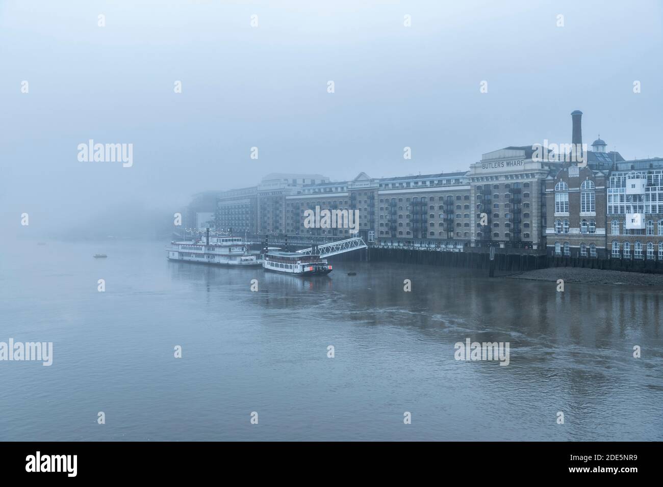 Butlers Wharf Pier and River Thames in thick fog and mist, on a cool winter morning in the city in foggy and misty moody weather during Covid-19 Coronavirus lockdown, England, UK Stock Photo