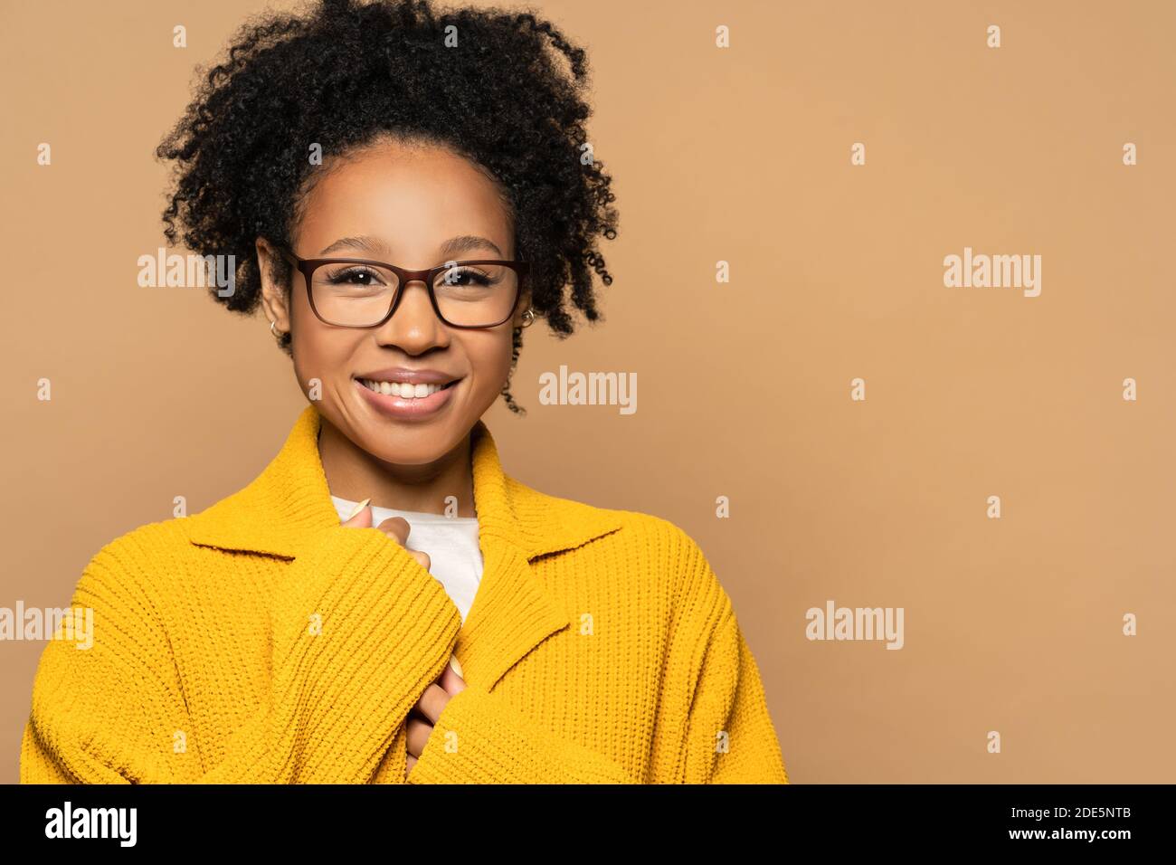 Confident happy African American young woman in yellow cardigan wearing spectacles, looking at camera. Smiling mixed race girl wear glasses isolated o Stock Photo