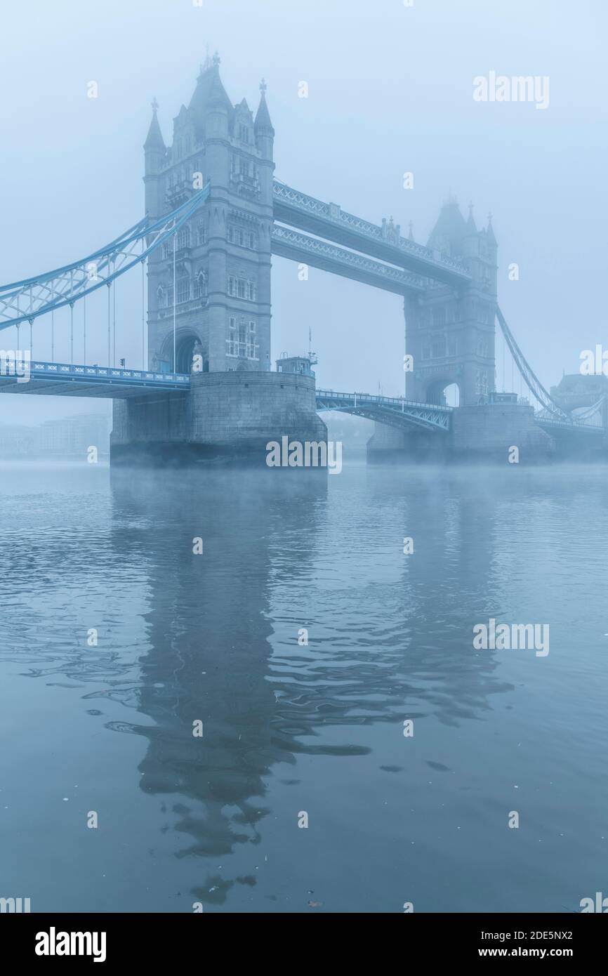 Tower Bridge and River Thames in foggy and misty blue atmospheric and moody weather conditions in London City Centre on Coronavirus Covid-19 lockdown day one, England, UK Stock Photo