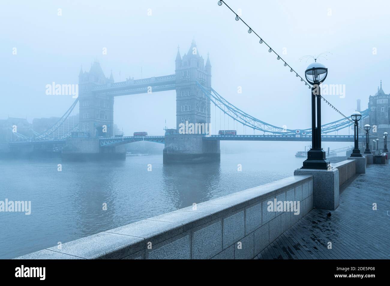 Tower Bridge and Red London Bus driving over River Thames in foggy and misty atmospheric and moody weather conditions on Coronavirus Covid-19 lockdown day one, England, UK Stock Photo