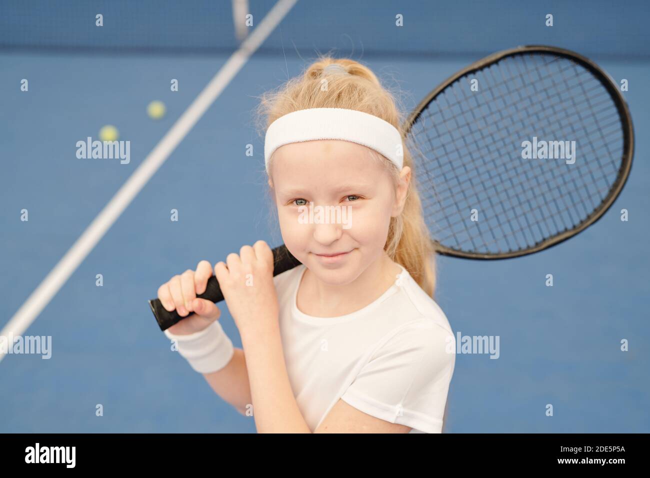Little Tennis Rackets Adorable little tennis player in white activewear holding racket on ...