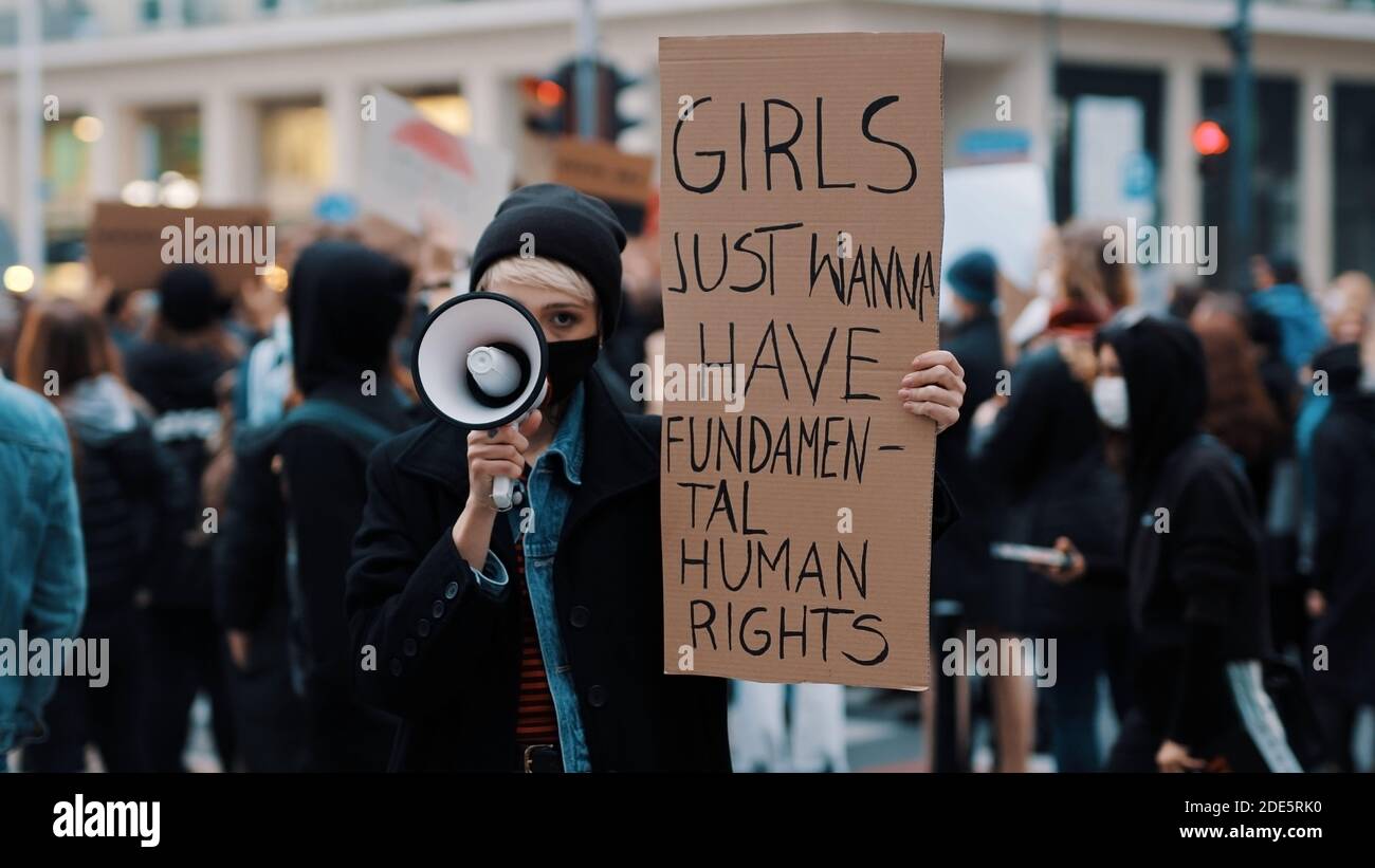 Girls just wanna have fundamental human rights. Woman march anti-abortion protest, woman holding banner and spaking into the megaphone. High quality photo Stock Photo