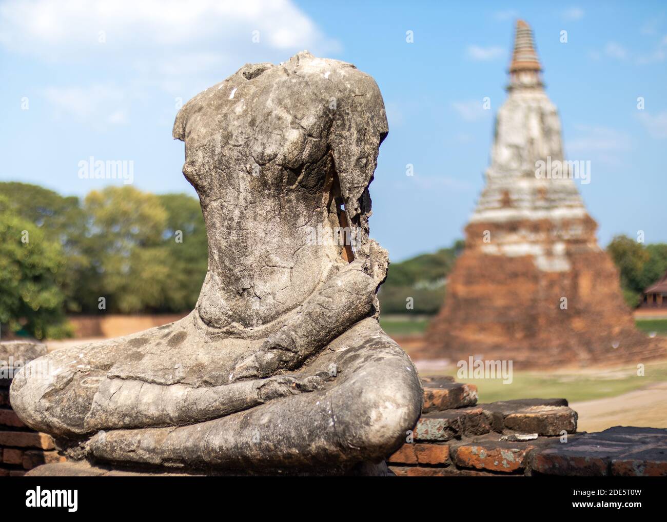 Headless and armless statue of Buddha seated in lotus position made of stone, stupa made of