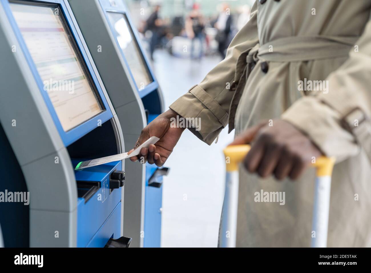 Black traveler man using self check-in machine kiosk service at airport, scans code on boarding ticket. Close up. Stock Photo