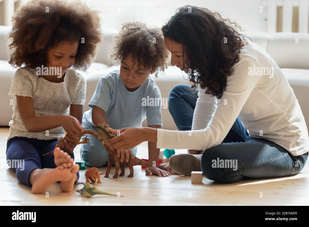 Pleasant black female tutor explaining children interesting facts about dinosaurs Stock Photo