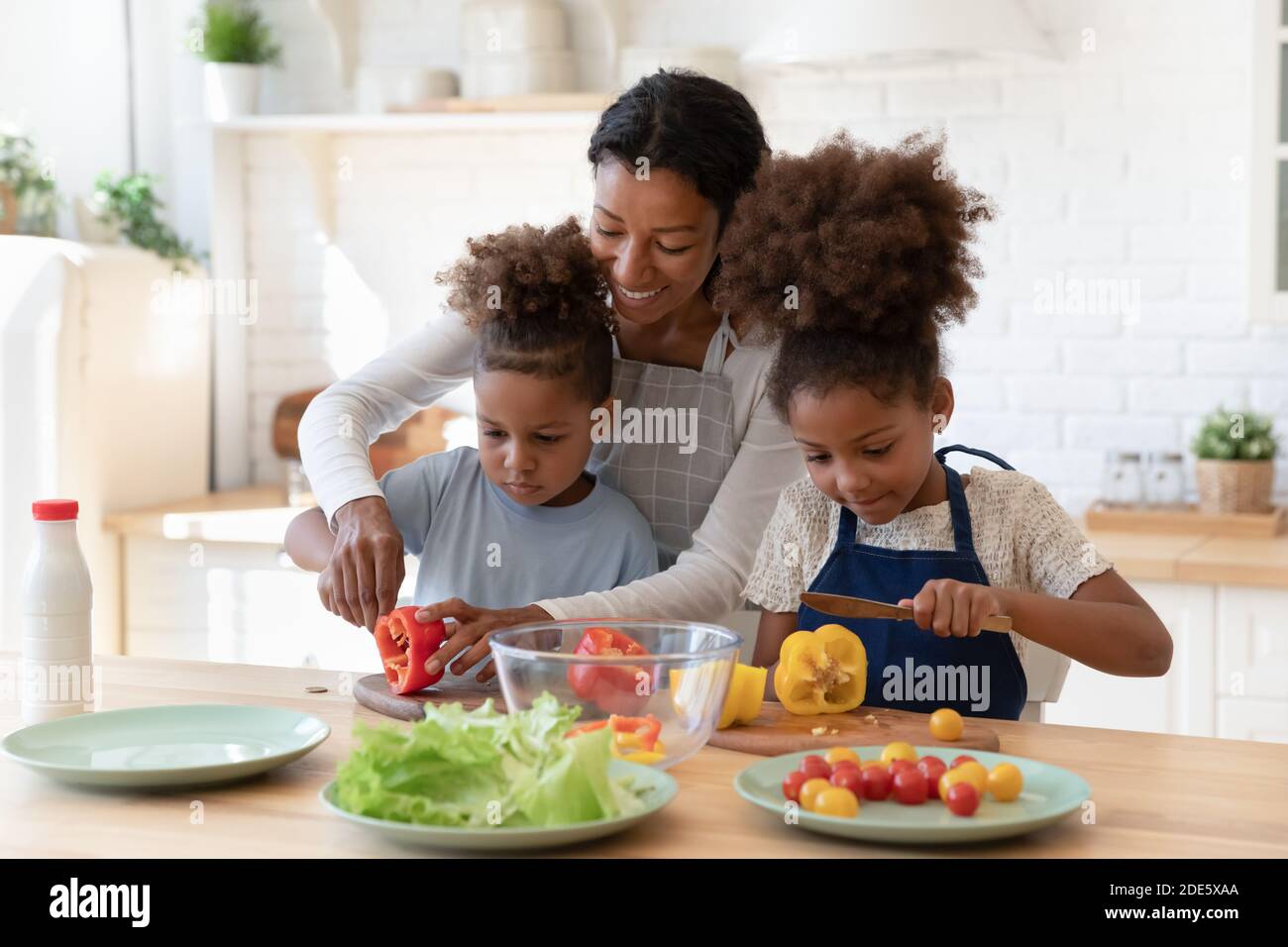 Patient african mom teaching son and daughter to prepare salad Stock Photo