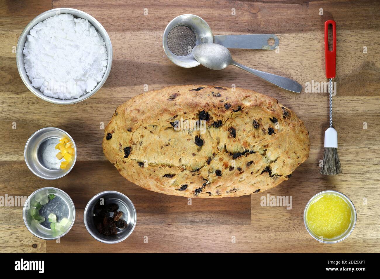 freshly baked traditional Saxon Christmas Stollen with some baking ingredients on wooden background Stock Photo