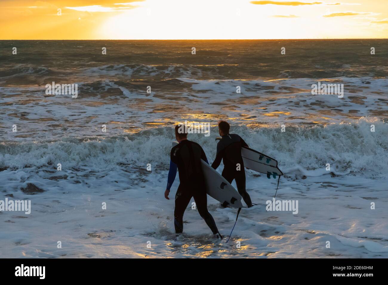 England, East Sussex, Eastbourne, Birling Gap, The Seven Sisters Cliffs and Beach, Two Male Surfers Walking on Beach Carrying Surfboards Stock Photo