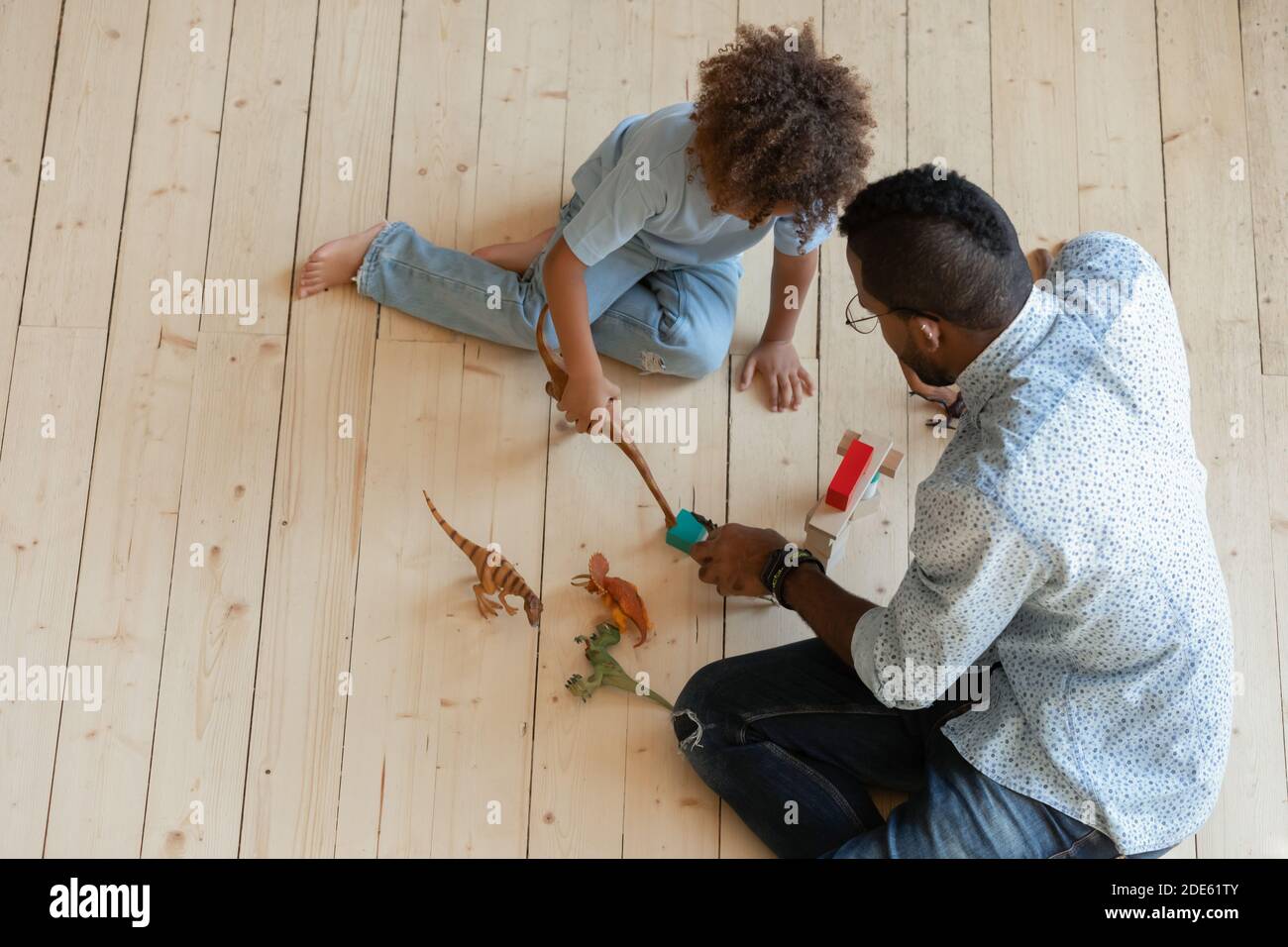 African uncle and little nephew playing with dinosaur action figures Stock Photo