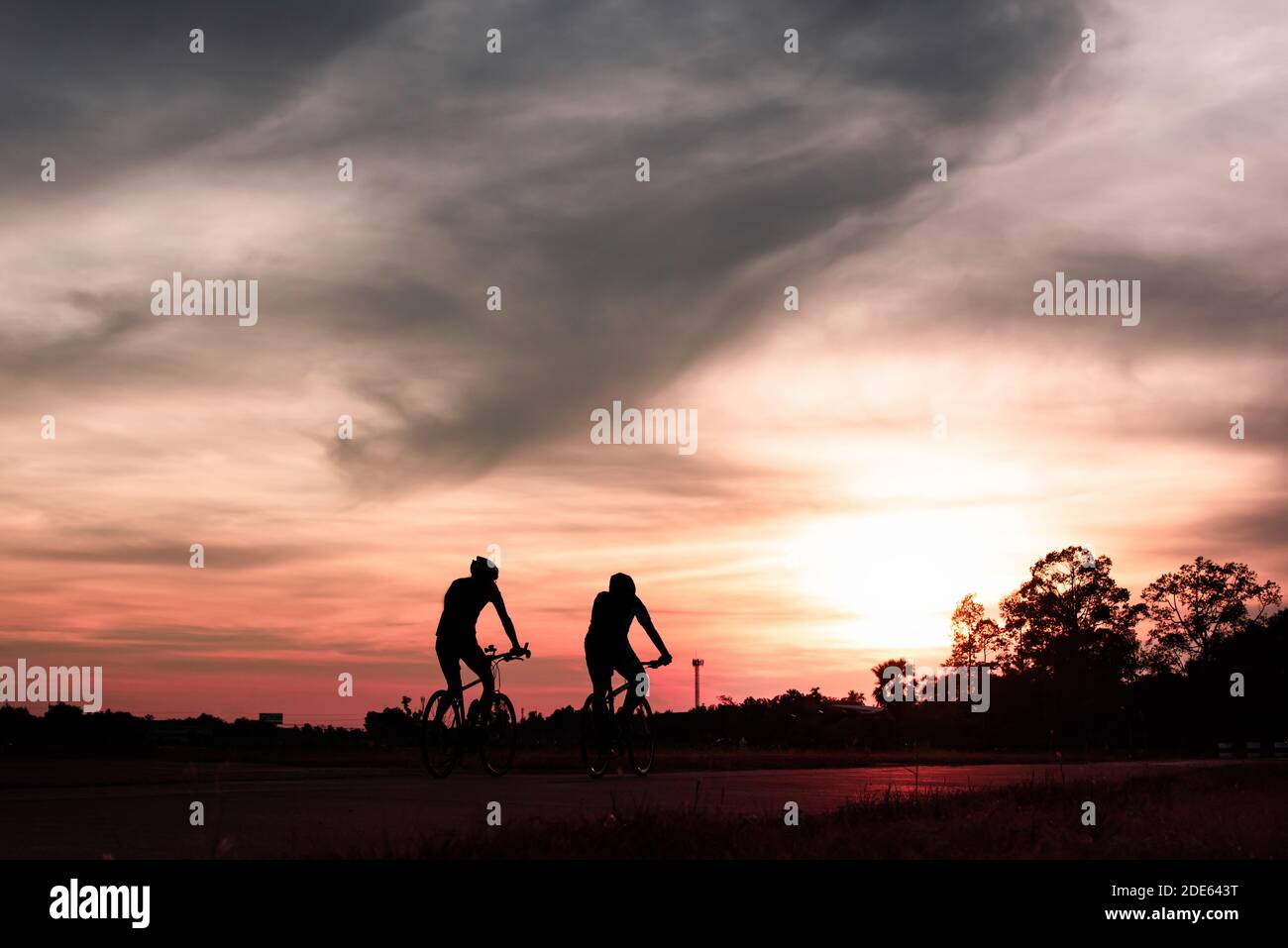 The couple of cyclist riding the road bike at sunset,silhouette image. Stock Photo