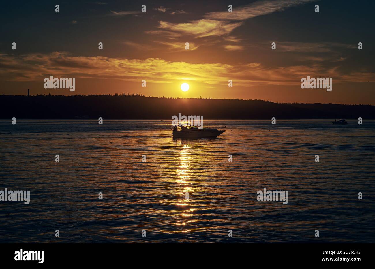 Boat on the sea while a colorful sunset Stock Photo - Alamy