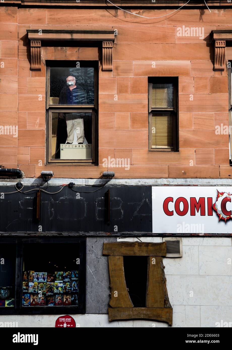 Cardboard cut out of masked man standing in apartment window Stock Photo