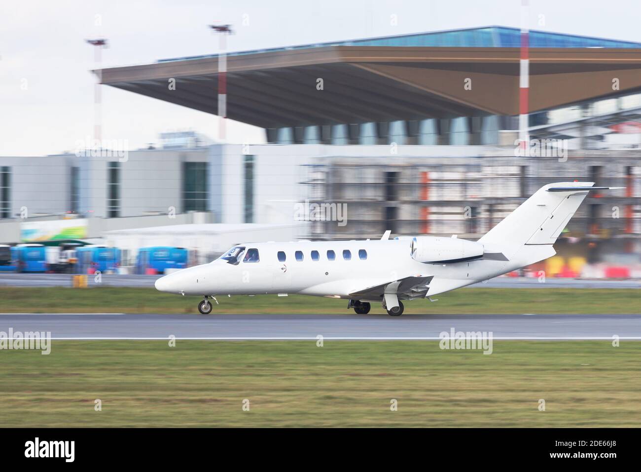 Side view of small Private business Jet taxing on runway for take off, in motion, airport building on background/Business, travel, private aviation co Stock Photo