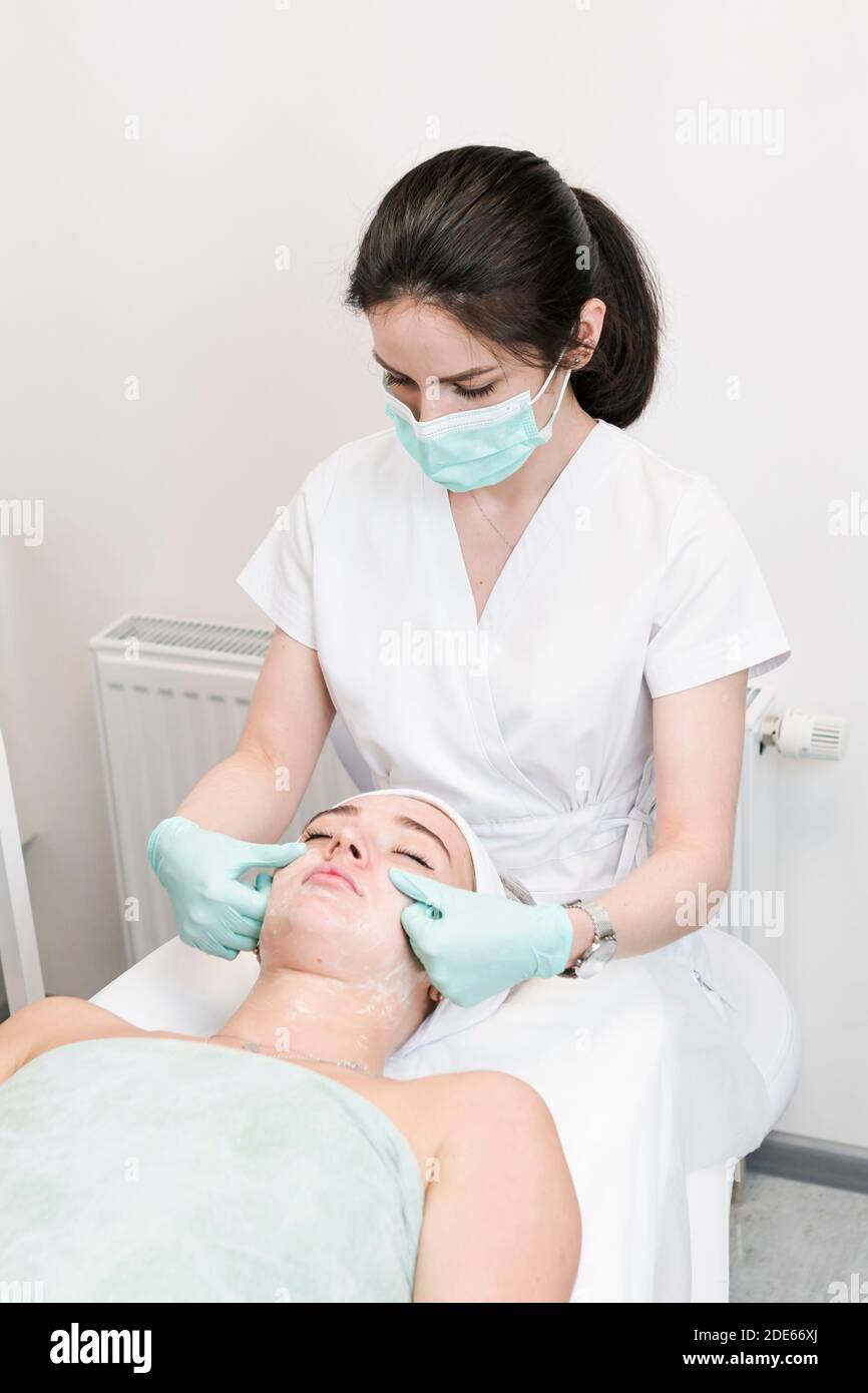 The young female client of cosmetic salon having a face cleaning procedure. The doctor cosmetologist cleaning skin. Concepts of skin care and beauty s Stock Photo