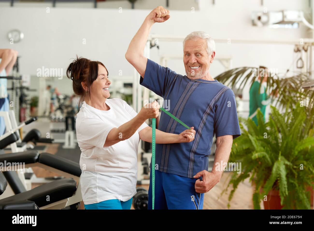 Funny senior man flexing his muscles at gym. Stock Photo