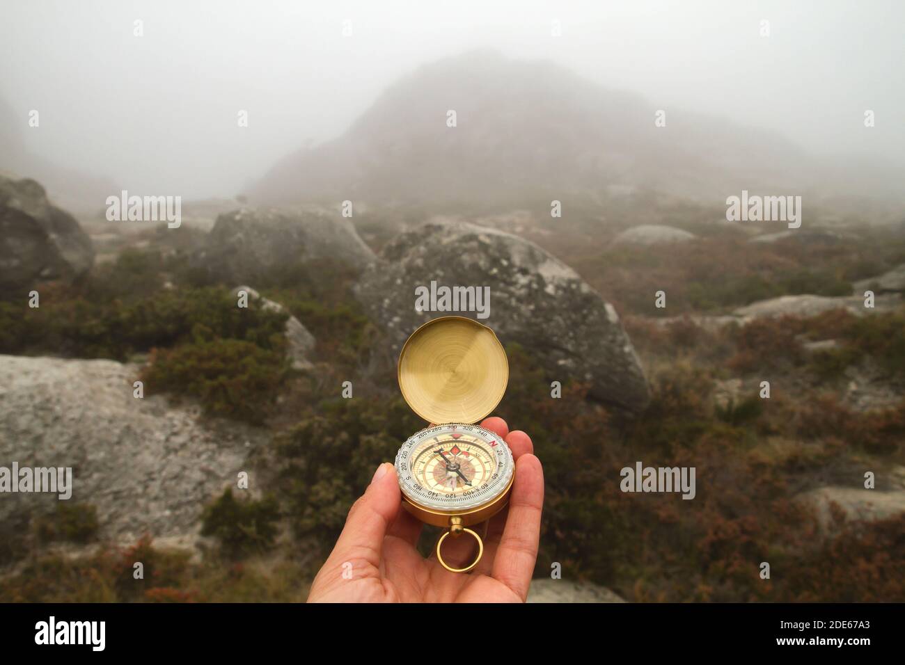Explorer orienteering with compass in a foggy day Stock Photo