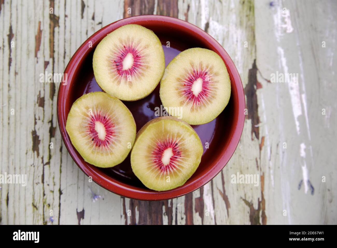 Four halves of pink kiwi on a rustic board Stock Photo - Alamy