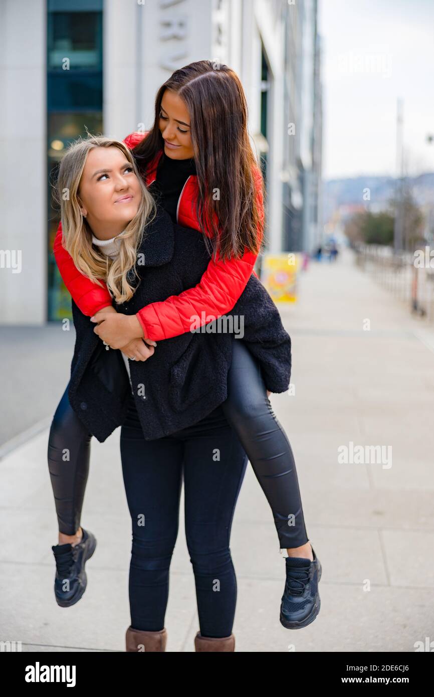 Two Close Woman Friends Having Fun and Piggybacking In City Stock Photo