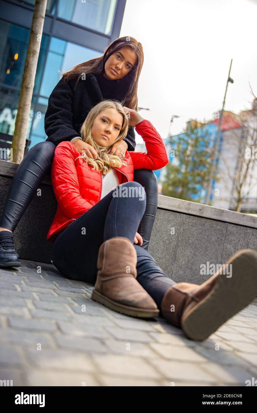 Portrait Of Two Beautiful Best Friends Sitting Togehter In City Stock Photo