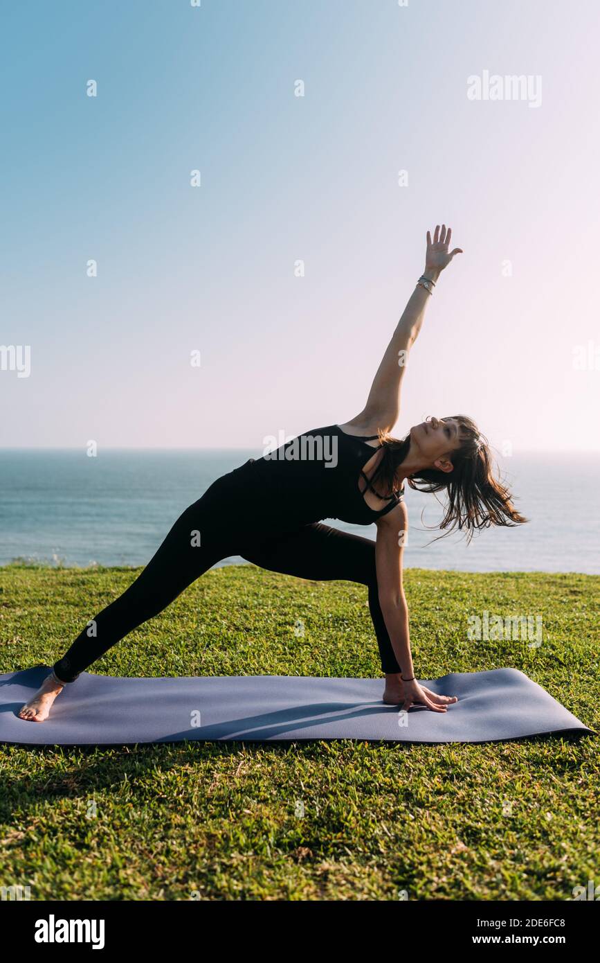 Vertical portrait of a slim woman practicing yoga outside the home. Copy space Stock Photo