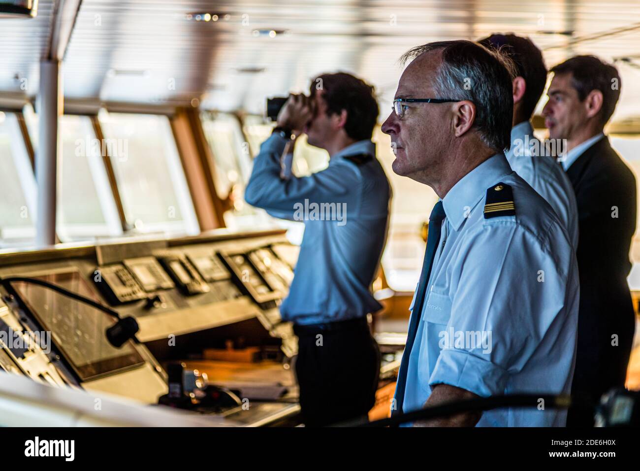 Captain Gilles Marré (front) and officers of the Pont Aven of Brittany Ferries stand on the bridge as the ferry enters the port of Cork, Ireland. One officer observes the coast through binoculars. Stock Photo