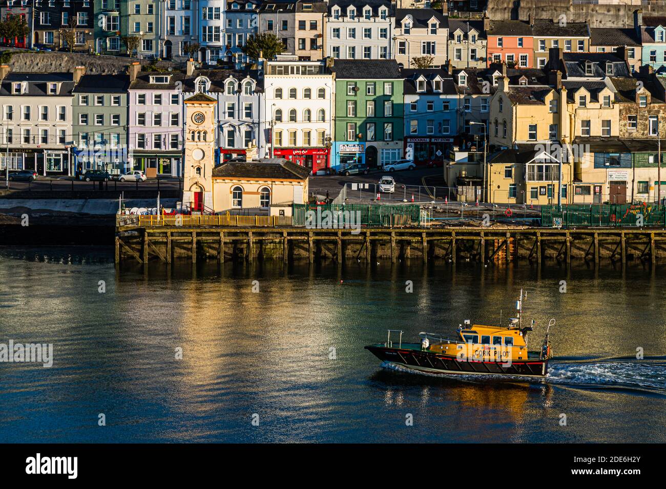 The pilot boat "Cork Pilot" passes the quay of Cobh, County Cork, Ireland, with its distinctive yellow clock tower. Cobh, formerly known as Queenstown, was the Titanic's last port of call in 1912. Stock Photo