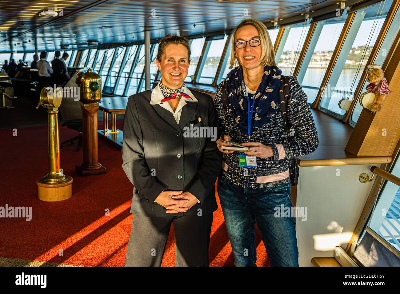 Entertainment manager Julie Moranges (left) answers questions from journalist Angela Berg (right) on the bridge of the Pont Aven of Brittany Ferries. In the background, the coast passes by as the ferry enters the port of Cork, Ireland. Stock Photo