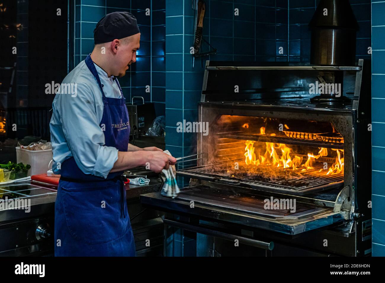 The Josper charcoal grill at The Grill restaurant, Dunloe Hotel & Gardens near Killarney, Ireland, cooks domestic Black Angus beef over an open flame. A cook turns the pieces of meat with tongs. Stock Photo