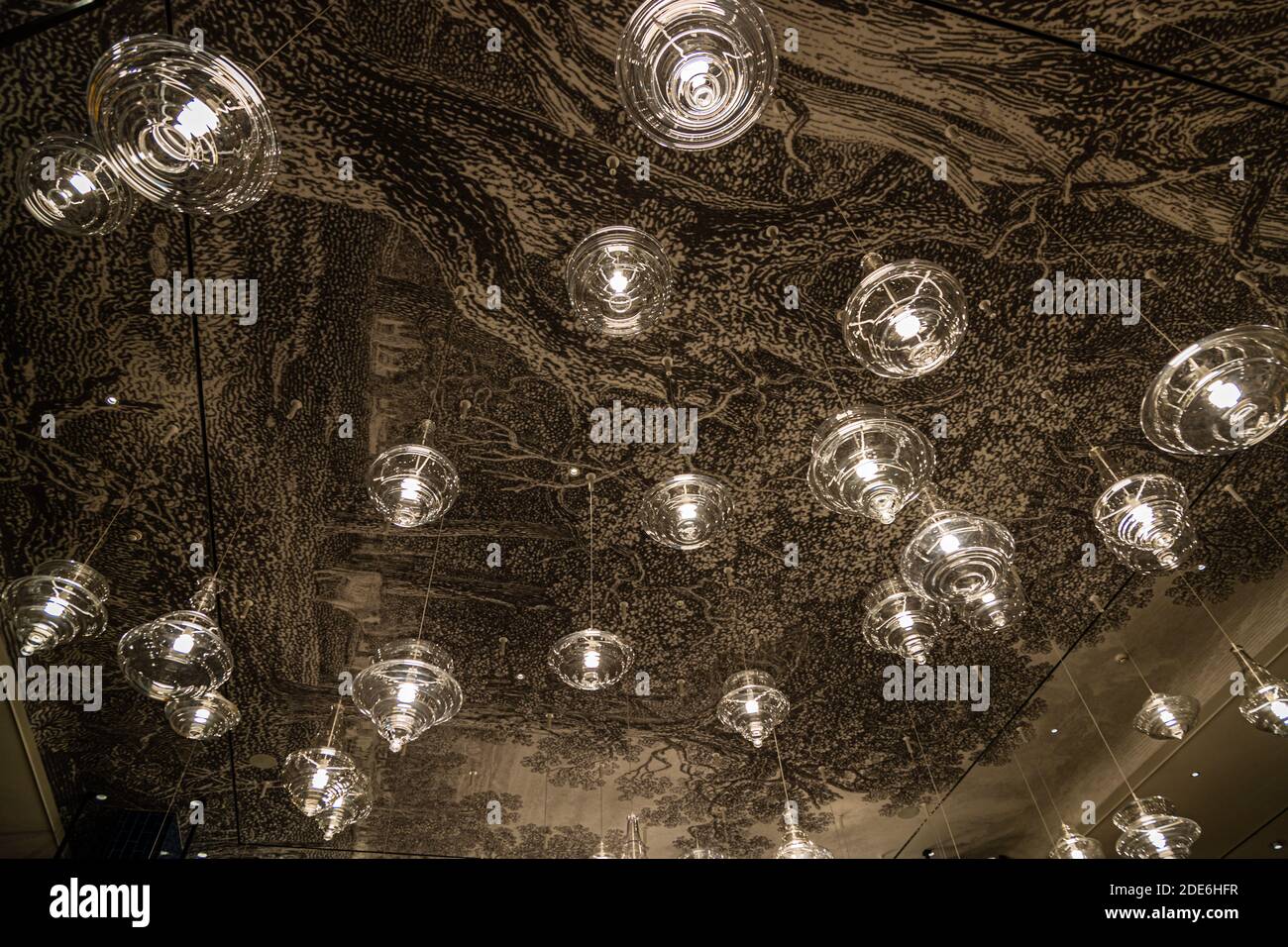 The ceiling of The Grill restaurant at the Dunloe Hotel & Gardens near Killarney, Ireland, is printed with a large-scale tree motif. Dozens of globe-shaped glass lamps hang in front of it. Stock Photo