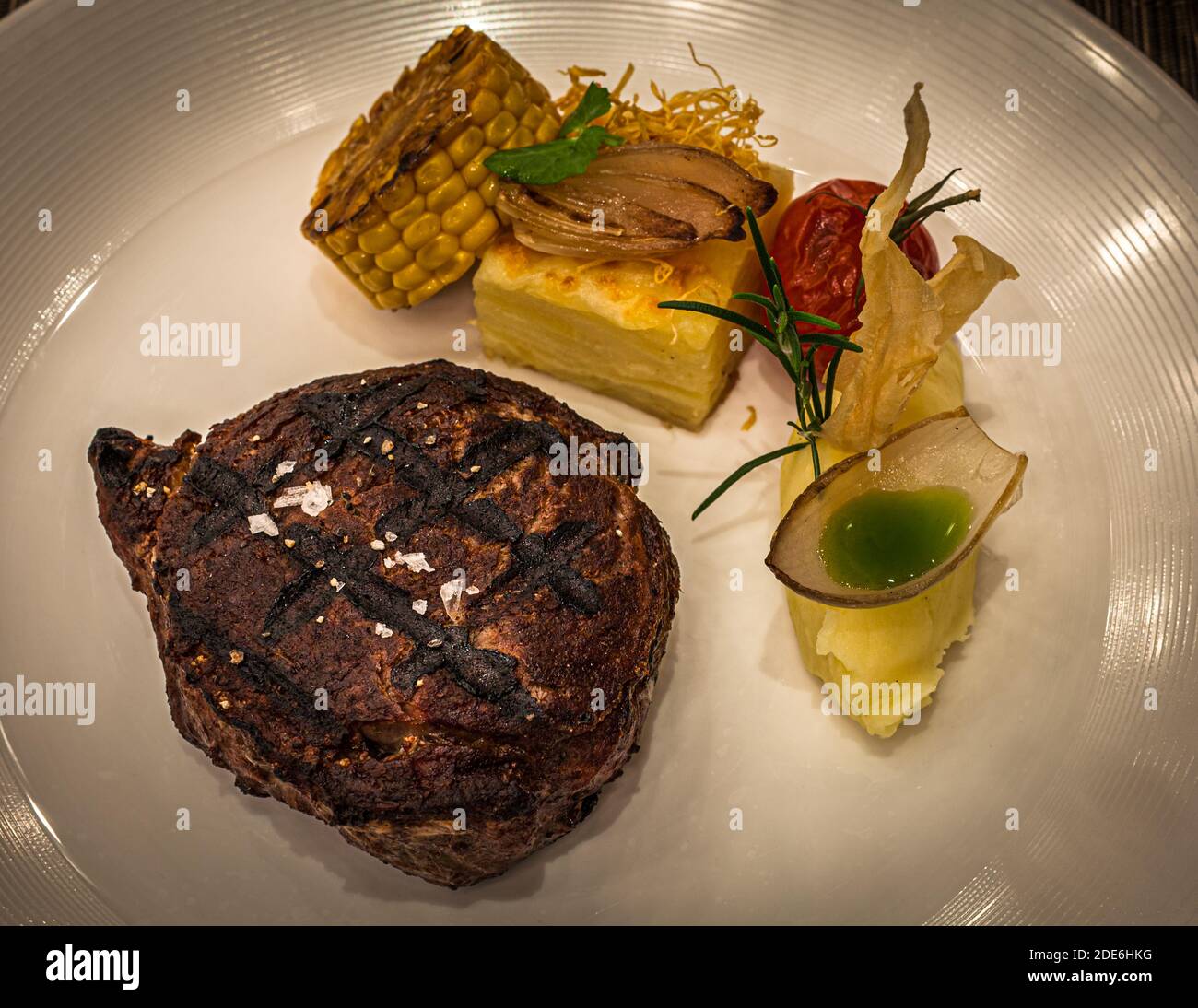 Ribeye of Black Angus from our own pasture, dry aged for 28 days with potato gratin and mashed potatoes with basil oil in an onion boat. The meat is prepared on the Josper Grill. Restaurant Dish in The Dunloe Hotel near Killarney, Ireland Stock Photo