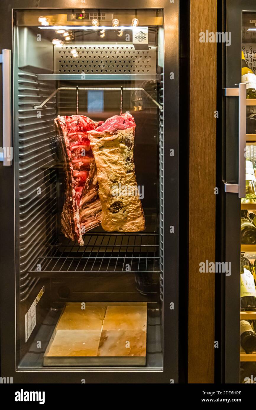 A side of beef matures in the glass-fronted dry-ageing cabinet at The Grill restaurant, Dunloe Hotel & Gardens near Killarney, Ireland. Beside it stands a wine fridge stocked with numerous bottles. Stock Photo