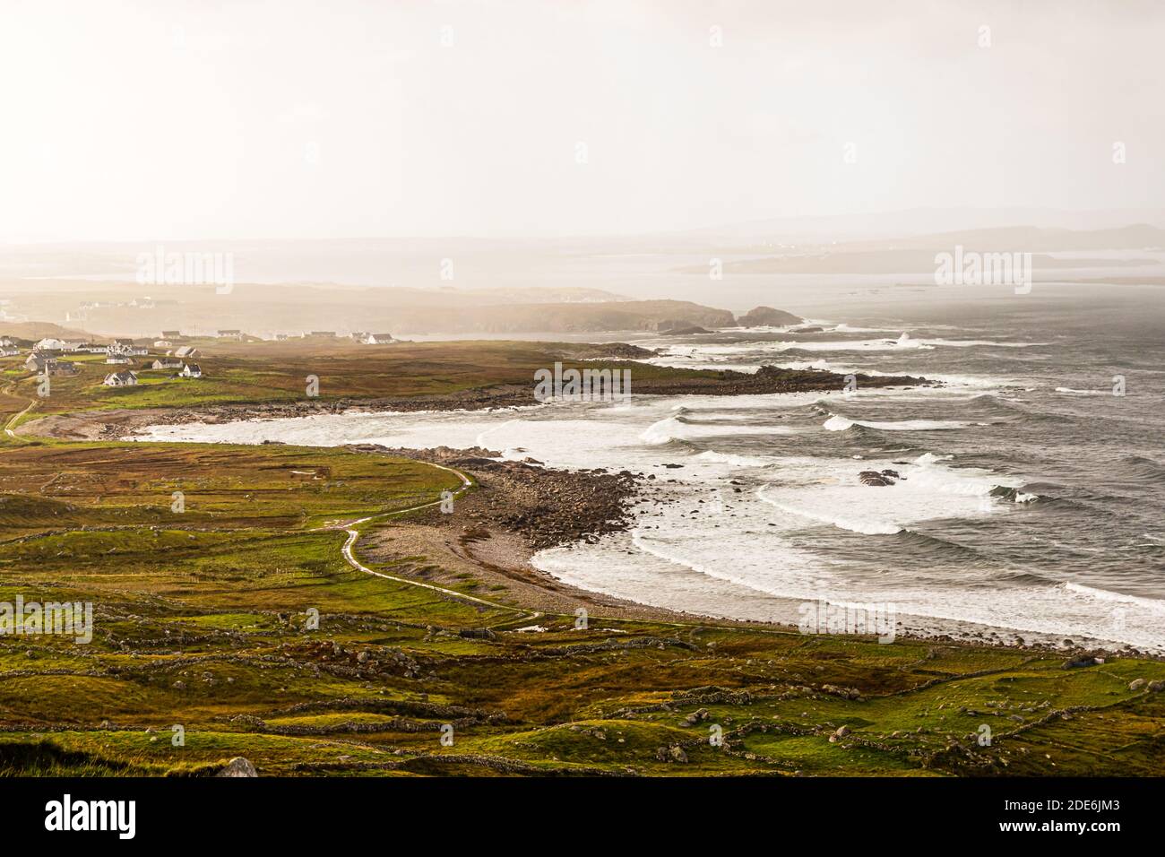 Foaming surf bursts along the rocky coastline of Ireland beside the R257 road in County Donegal. Waves break against the cliffs below the road. Stock Photo