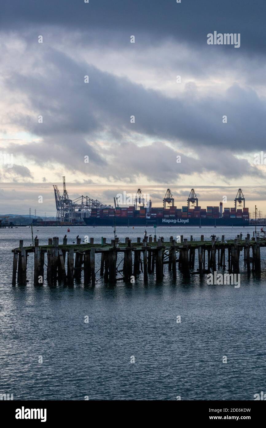 an atmospheric evening sunset over the port of southampton container docks with cranes and an old wooden pier Stock Photo