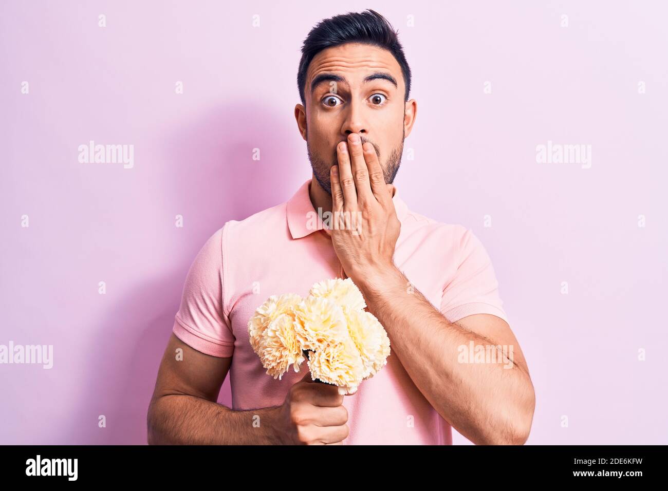 Young handsome romantic man with beard holding bouquet of flowers over ...