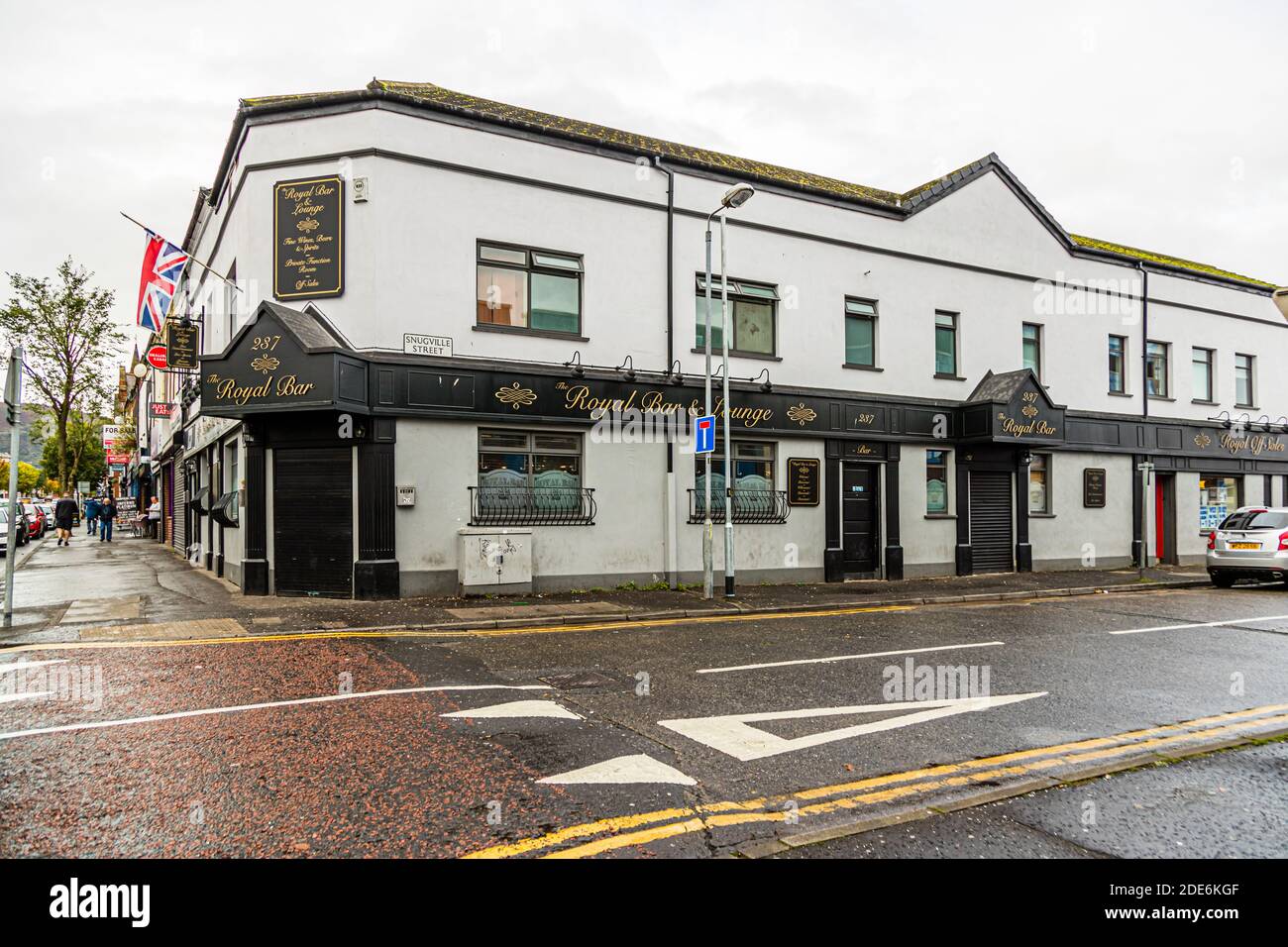 The Royal Bar & Lounge on the corner of Shankill Road and Snugville Street in Belfast, Northern Ireland, displays gold lettering on its whitewashed facade and flies a British flag; the house number 287 is visible at the entrance. Stock Photo