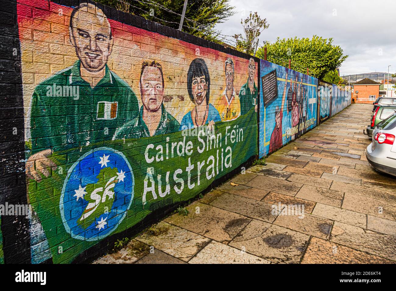 A mural titled "Cairde Sinn Féin Australia" on Conway Street, Belfast, Northern Ireland, shows the portraits of five supporters in front of the organisation's logo in the colours of the Australian flag. Stock Photo