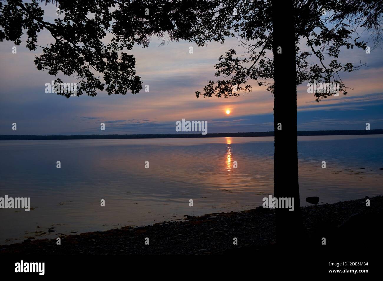 A quiet, orange sunrise across Union River Bay, rising over Mt Dessert Island in Surry, Maine. Stock Photo