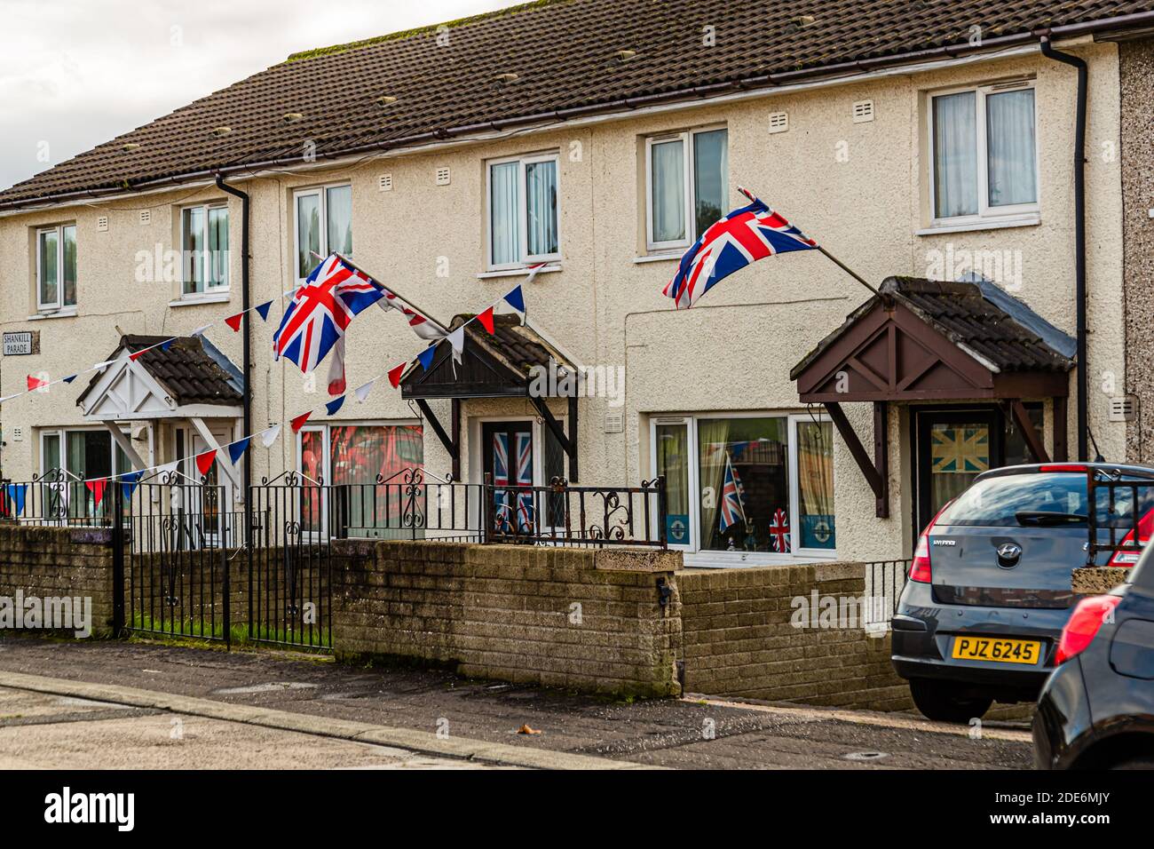 Union Jack flags and colourful bunting decorate a row of terraced houses on Donnell Parade in the Lower Shankill, Belfast, Northern Ireland. Stock Photo
