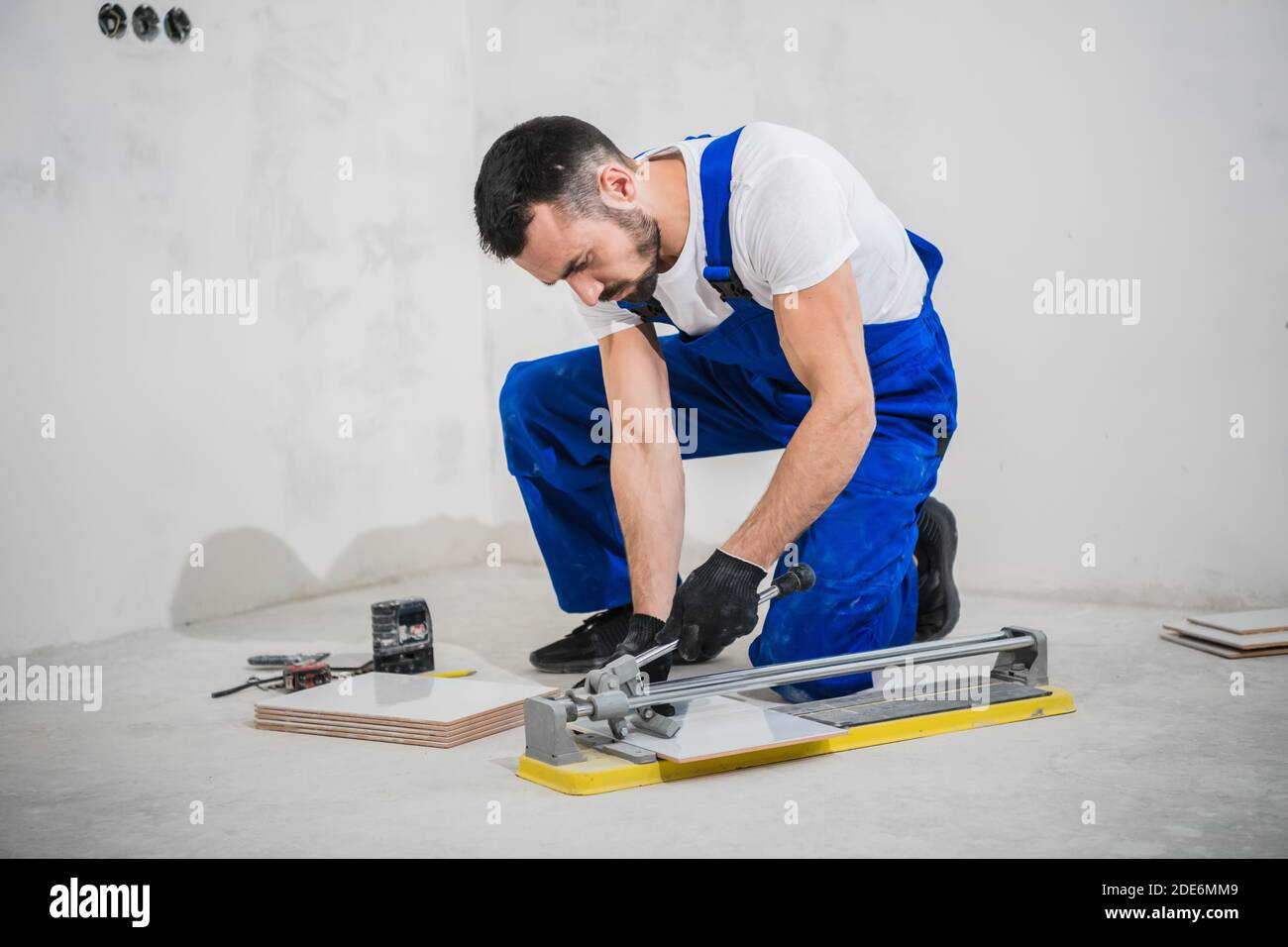 Young workman cuts tiles with a special tool Stock Photo