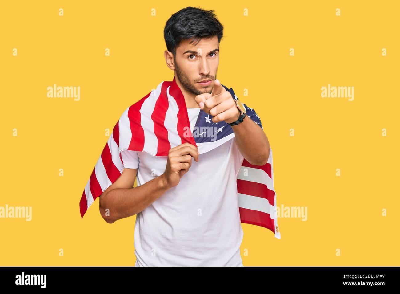 Young handsome man holding united states flag pointing with finger to ...