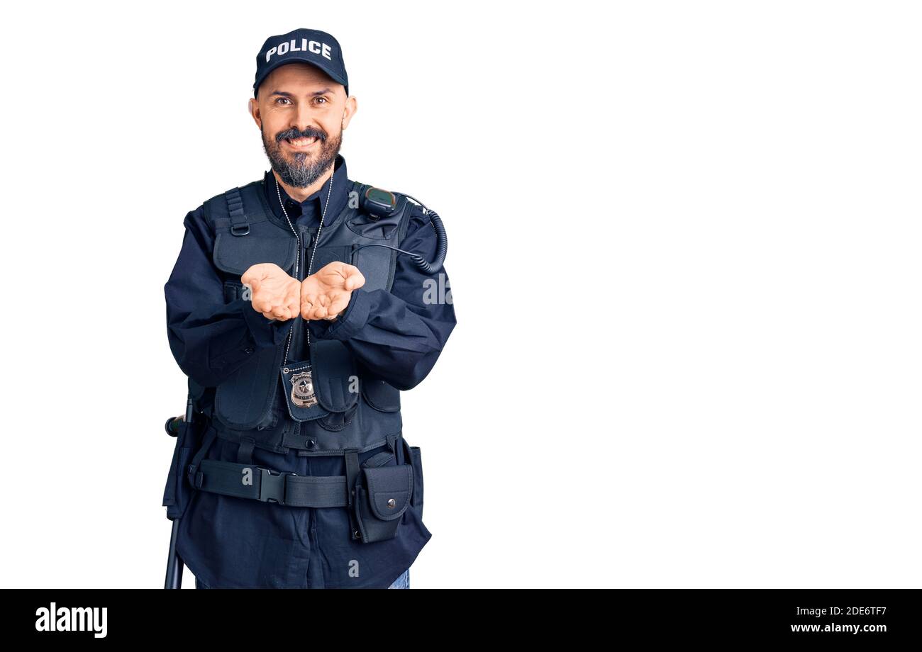 Young handsome man wearing police uniform smiling with hands palms together receiving or giving gesture. hold and protection Stock Photo