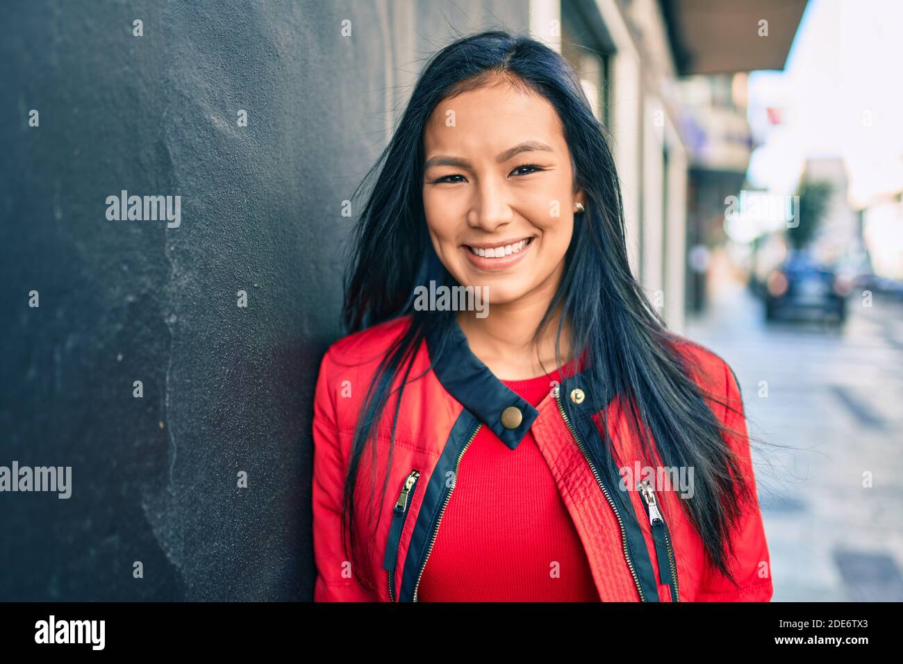 Young latin woman smiling happy leaning on the wall at the city Stock ...
