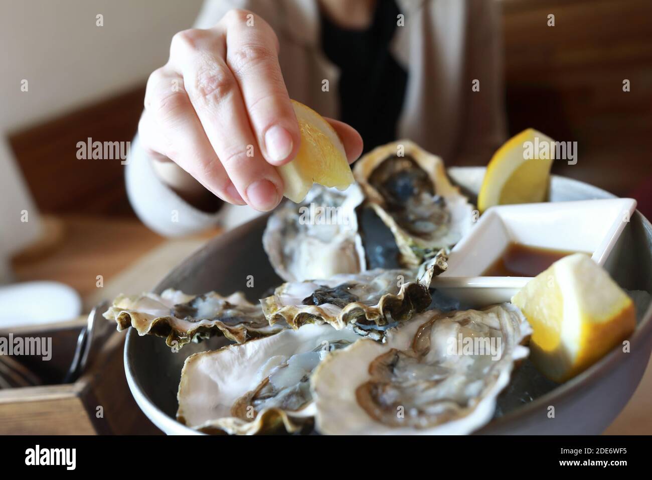 Woman squeezes lemon juice on oysters in restaurant Stock Photo Alamy