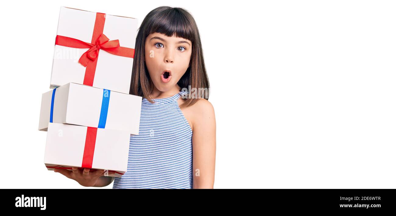 Young little girl with bang holding gifts scared and amazed with open mouth  for surprise, disbelief face Stock Photo - Alamy