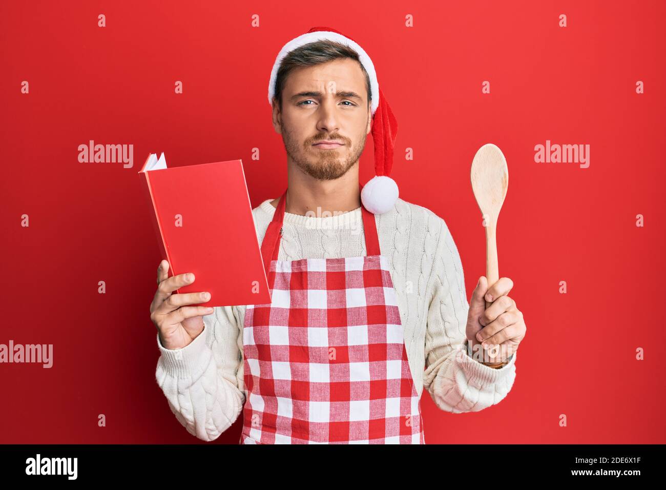 Handsome caucasian man cooking wearing baker apron and christmas hat ...