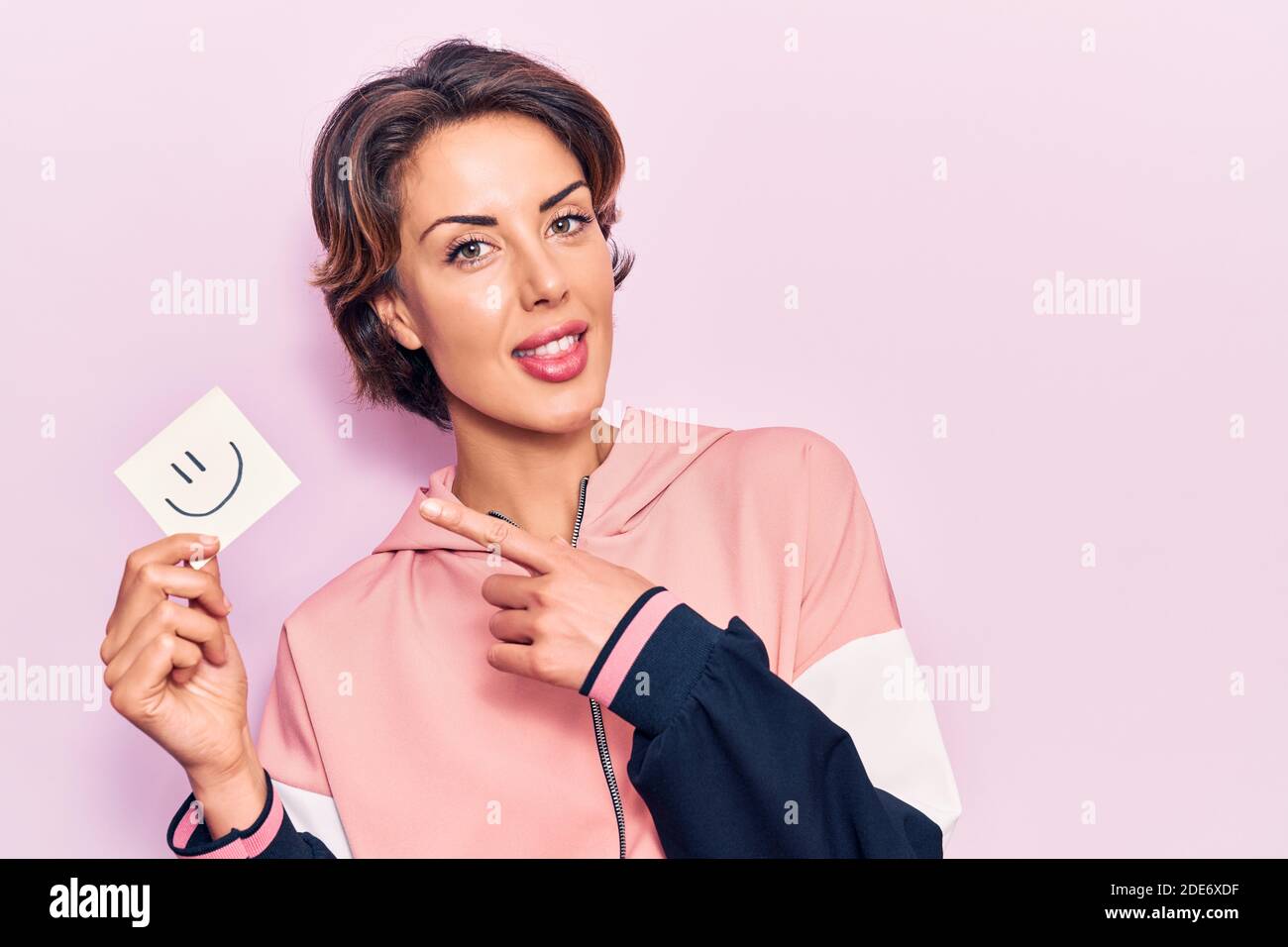 Young beautiful woman holding smile emoji reminder smiling happy