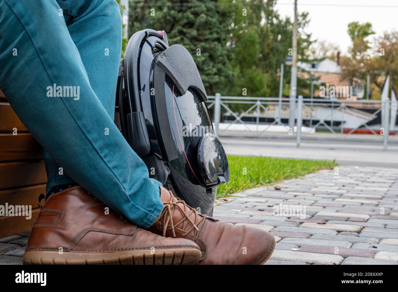 Electric mono wheel, innovative personal vehicle, self-balancing electric unicycle, ecological urban transport of the future near a man in jeans and b Stock Photo